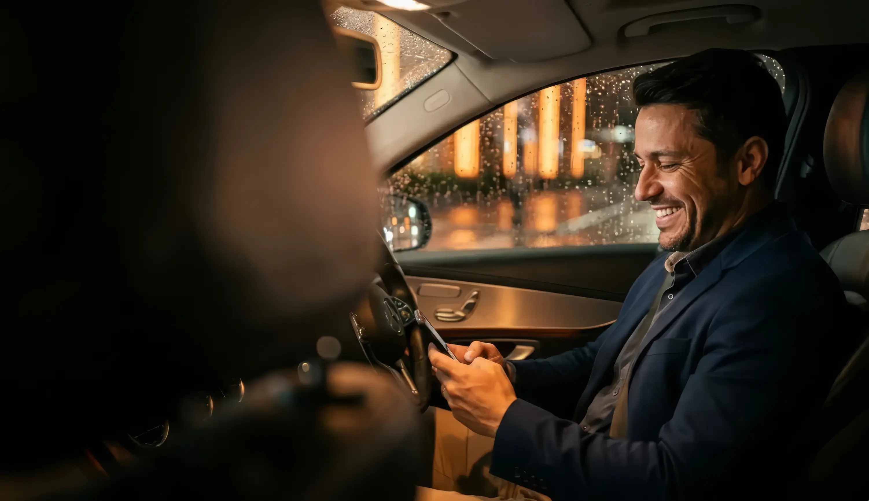 Motorista de aplicativo sorrindo ao consultar a proposta no celular dentro do carro à noite na cidade de São Paulo